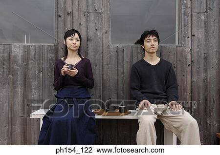 Stock Image - Young couple sitting on a bench. Fotosearch