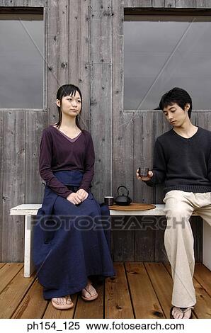 Young couple sitting on a bench View Large Photo Image Stock Photography - Young couple sitting on a bench. Fotosearch