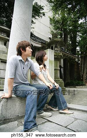 Stock Photo - Young couple sitting on a concrete seat. Fotosearch