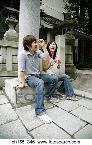Young couple sitting on a concrete seat and laughing View Large Photo Image Stock Photograph - Young couple sitting on a concrete seat and laughing. Fotosearch
