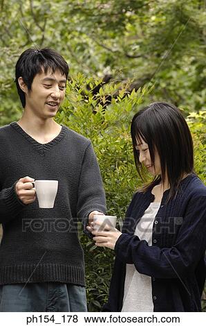 Young couple standing together holding coffee cups View Large Photo Image Stock Photo - Young couple standing together holding coffee cups. Fotosearch
