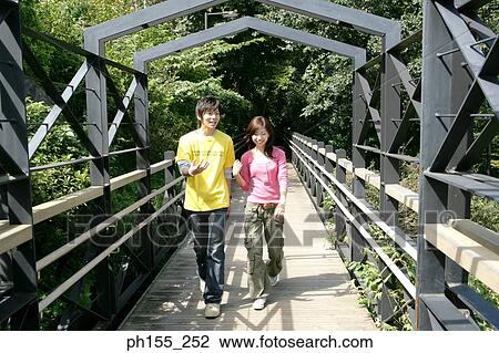 Young couple walking on a footbridge View Large Photo Image Stock Image - Young couple walking on a footbridge. Fotosearch