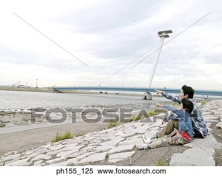 Stock Photography - Young man and his son pointing forward. Fotosearch