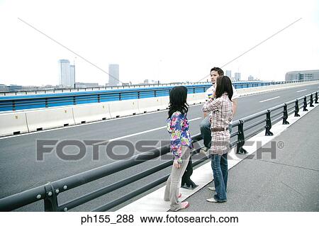 Young man and two young women standing on the road View Large Photo Image Stock Photo - Young man and two young women standing on the road. Fotosearch