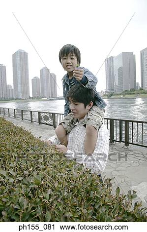 Stock Image - Young man carrying his son on his shoulders. Fotosearch
