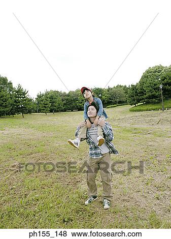 Stock Photo - Young man carrying his son on his shoulders. Fotosearch