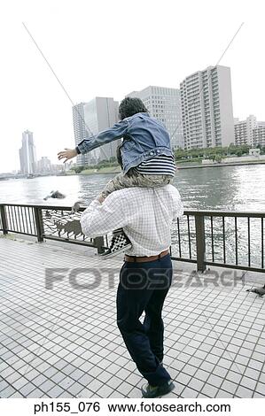 Young man carrying his son on his shoulders View Large Photo Image Stock Photograph - Young man carrying his son on his shoulders. Fotosearch