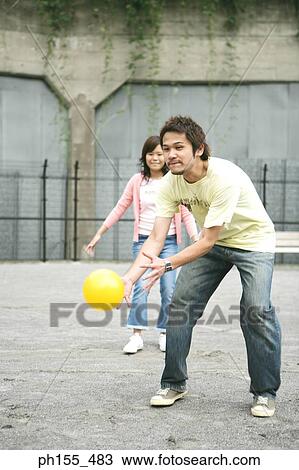 Young man holding a ball with a young woman standing behind him View Large Photo Image Stock Image - Young man holding a ball with a young woman standing behind him. Fotosearch