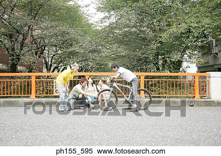 Young man sitting on a bicycle with four friends beside him View Large Photo Image Stock Photography - Young man sitting on a bicycle with four friends beside him. Fotosearch