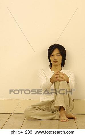 Stock Image - Young man sitting on the floor. Fotosearch