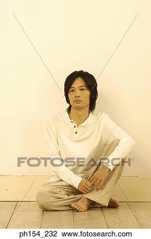 Stock Image - Young man sitting on the floor with his legs crossed. Fotosearch