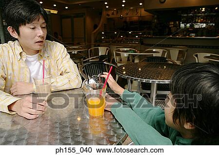 Young man sitting with his son in a restaurant View Large Photo Image Stock Image - Young man sitting with his son in a restaurant. Fotosearch