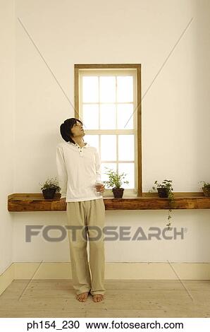 Young man standing in front of a window with a glass View Large Photo Image Stock Image - Young man standing in front of a window with a glass. Fotosearch