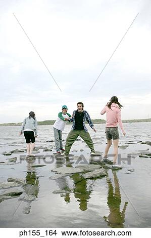 Young people standing in the middle of a river View Large Photo Image Picture - Young people standing in the middle of a river. Fotosearch