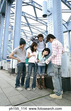 Picture - Young people standing together and looking at a map. Fotosearch