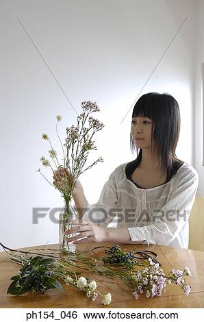 Young woman arranging a flower vase View Large Photo Image Stock Photograph - Young woman arranging a flower vase. Fotosearch