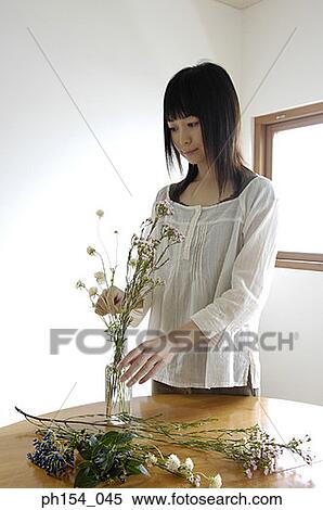 Stock Photography - Young woman arranging a flower vase. Fotosearch