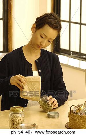 Young woman filling a jar with beans View Large Photo Image Stock Photo - Young woman filling a jar with beans. Fotosearch