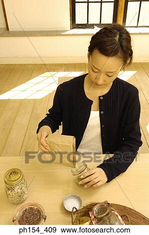 Young woman filling a jar with beans View Large Photo Image Stock Photo - Young woman filling a jar with beans. Fotosearch