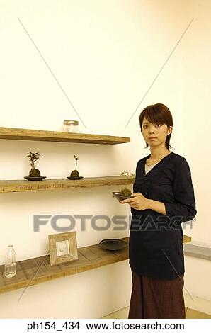 Young woman holding a potted plant View Large Photo Image Picture - Young woman holding a potted plant. Fotosearch
