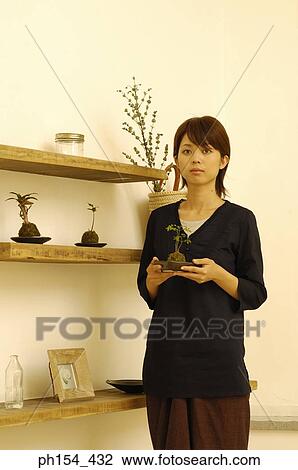 Stock Image - Young woman holding a potted plant. Fotosearch