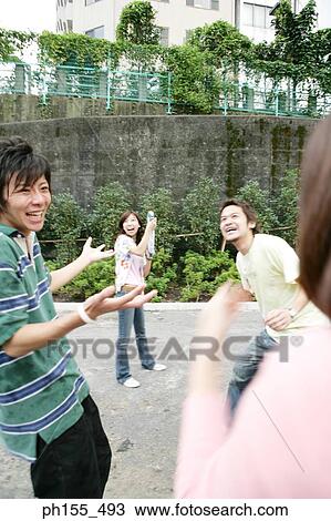 Stock Image - Young woman holding a squirt gun and standing with her friends. Fotosearch