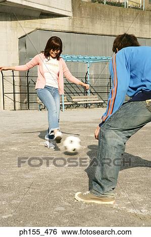 Young woman playing football with a young man View Large Photo Image Stock Photograph - Young woman playing football with a young man. Fotosearch