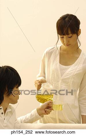 Young woman pouring tea into a young man's tea cup View Large Photo Image Stock Image - Young woman pouring tea into a young man's tea cup. Fotosearch