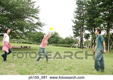 Young woman reaching for a ball with her two friends looking at her View Large Photo Image Stock Image - Young woman reaching for a ball with her two friends looking at her. Fotosearch
