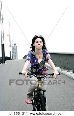 Young woman riding a bicycle View Large Photo Image Stock Image - Young woman riding a bicycle. Fotosearch