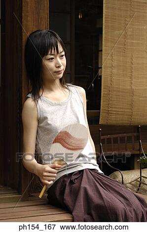 Young woman sitting and holding a folding fan View Large Photo Image Stock Photo - Young woman sitting and holding a folding fan. Fotosearch