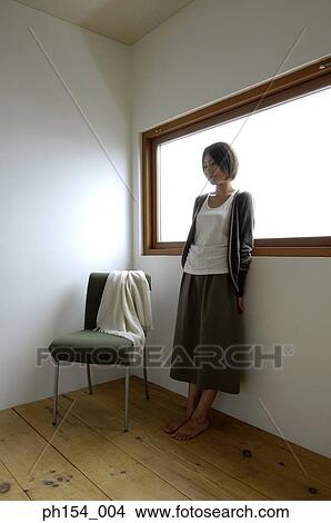 Picture - Young woman standing by a window. Fotosearch