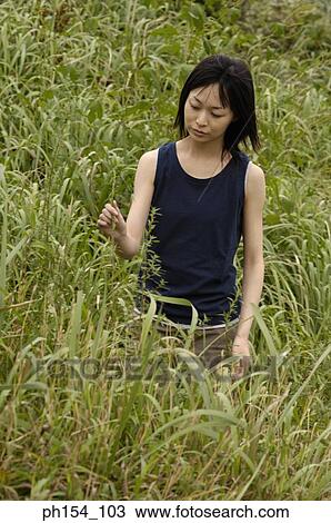 Young woman standing on a field View Large Photo Image Stock Image - Young woman standing on a field. Fotosearch