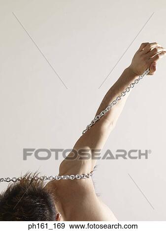 Stock Photo - A bare-chested man struggling with metal chain. Fotosearch