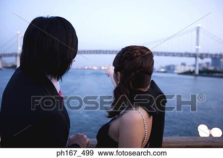 Stock Photo - A couple enjoying the sea view from cruise ship, rear view. Fotosearch