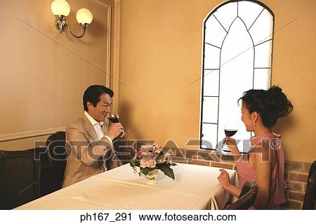 Stock Image - A couple in a restaurant having wine. Fotosearch