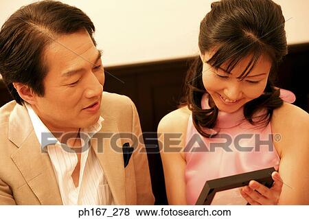 Stock Photo - A couple looking at a photo frame, close-up. Fotosearch