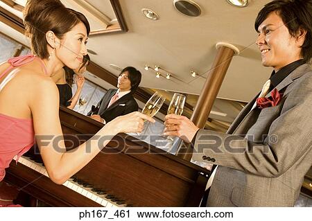 Stock Image - A couple making a toast by the piano. Fotosearch