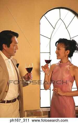 Stock Image - A couple relaxing by the window with wine. Fotosearch