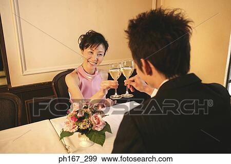 Stock Photo - A couple toasting with white wine. Fotosearch