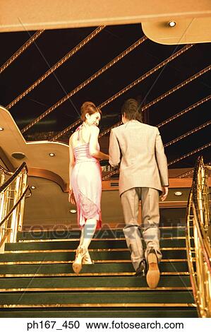 Stock Image - A couple walking up the stairs, rear view. Fotosearch