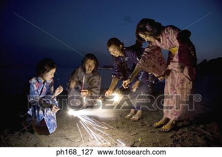 Stock Photo - A small group of people with sparklers at the beach. Fotosearch