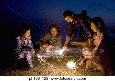 Stock Photo - A small group of people with sparklers at the beach. Fotosearch