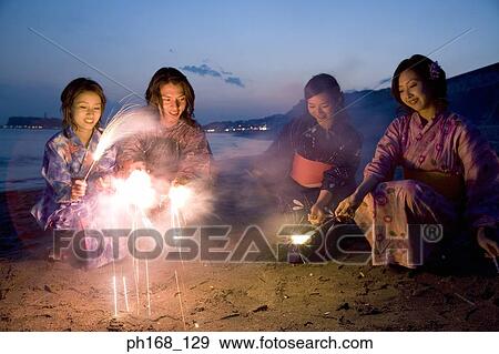A small group of people with sparklers at the beach View Large Photo Image Stock Photo - A small group of people with sparklers at the beach. Fotosearch
