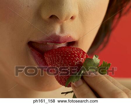 A woman biting into a strawberry. Close-up View Large Photo Image Stock Photo - A woman biting into a strawberry. Close-up. Fotosearch