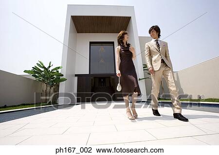 Stock Image - A young couple walking outdoors, low angle. Fotosearch