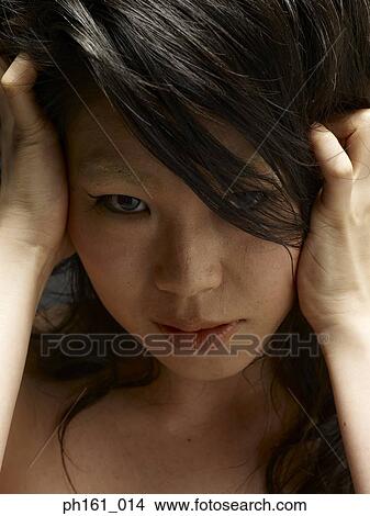 Picture - A young woman covering with hands in hair. Fotosearch