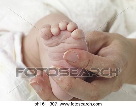 Stock Photo - An adult holding a newborn's feet. Fotosearch