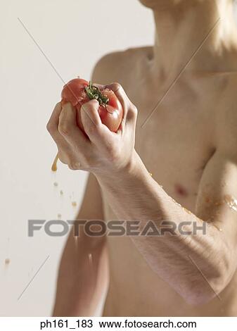 Bare-chested man squeezing a tomato in his hand View Large Photo Image Stock Image - Bare-chested man squeezing a tomato in his hand. Fotosearch