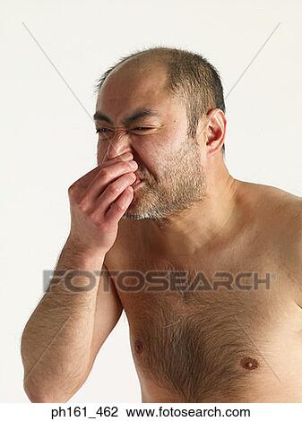Stock Image - Bare chested mature man holding his nose, side view. Fotosearch